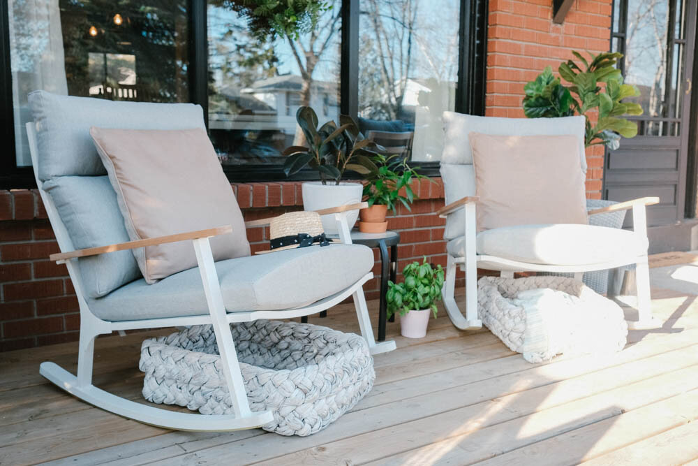 Front porch with red brick, black window trim, modern Eleya white and grey rocking chairs from Article, Tress white washed trays under chairs and two large white washed pot with fiddle leaf fig trees.