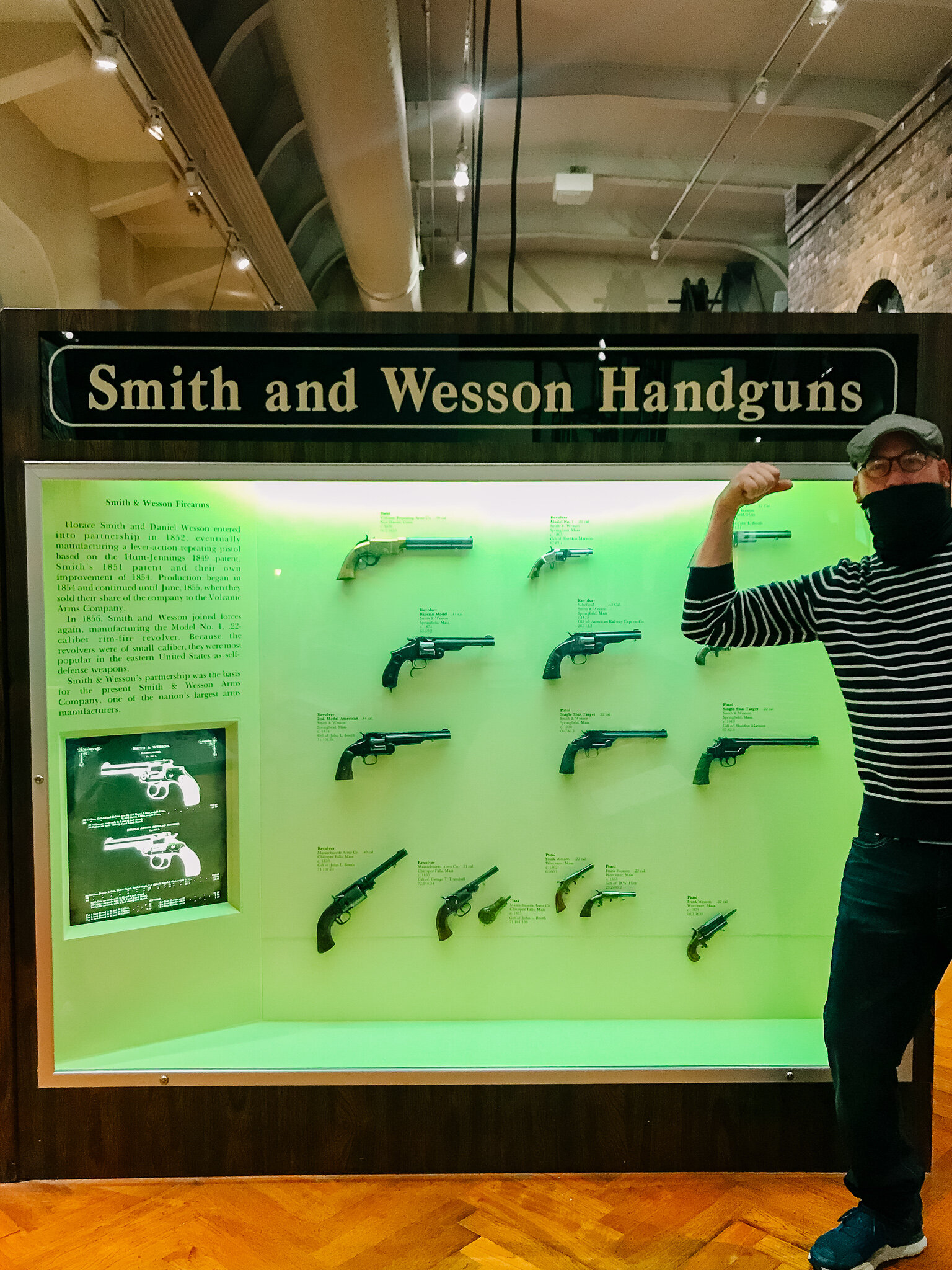 Man standing next to Smith and Wesson gun display at The Henry Ford Museum.