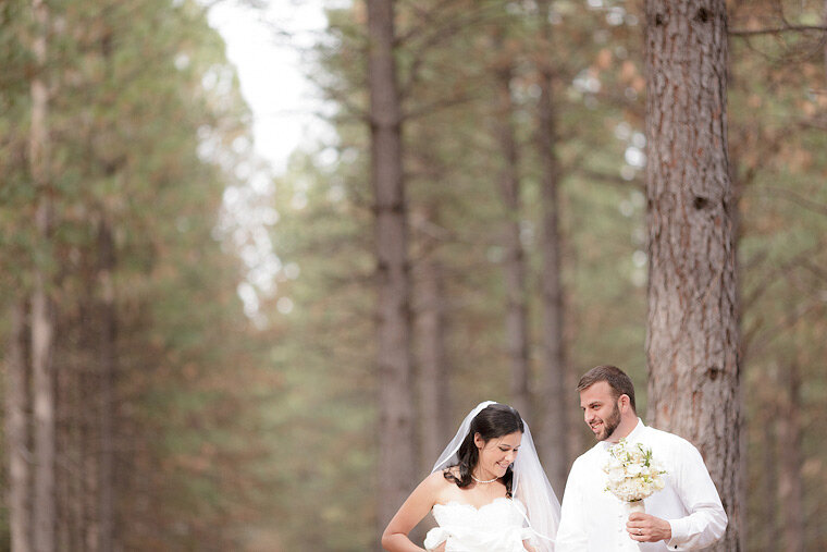 Bride and groom laugh together in the forest.