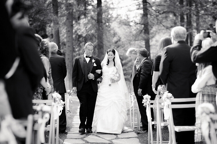 Bride and father walk down the aisle at Forest House Lodge's outdoor ceremony venue.