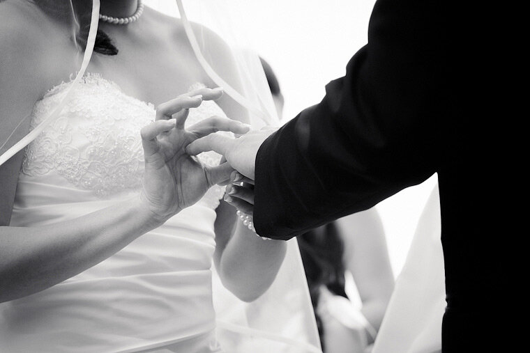 Bride places ring on groom's finger.