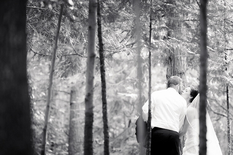 Groom kisses bride in the forest.