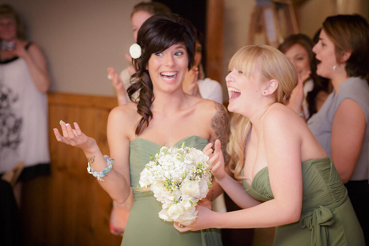 Bridesmaids laugh after catching the bouquet.