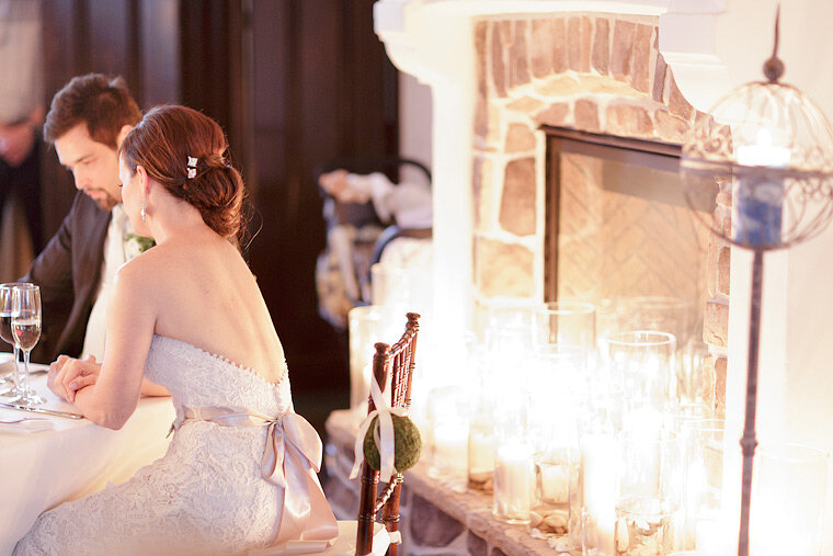 Bride and groom sit next to candles.
