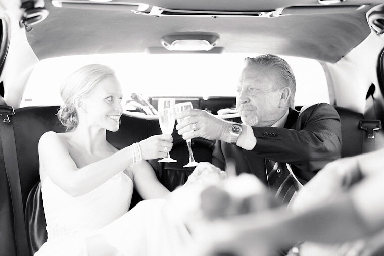 Bride and father toast champagne in limousine.