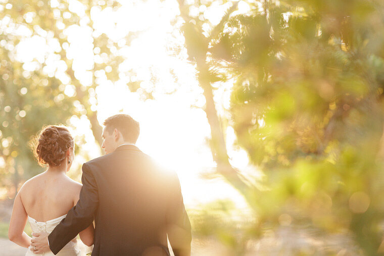 Bride and groom walk together at sunset.