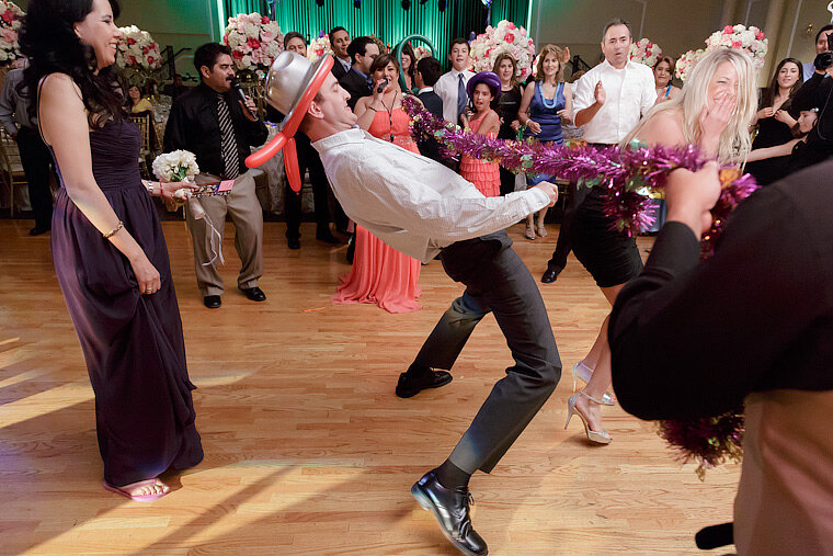 Man dances the limbo at a wedding reception.