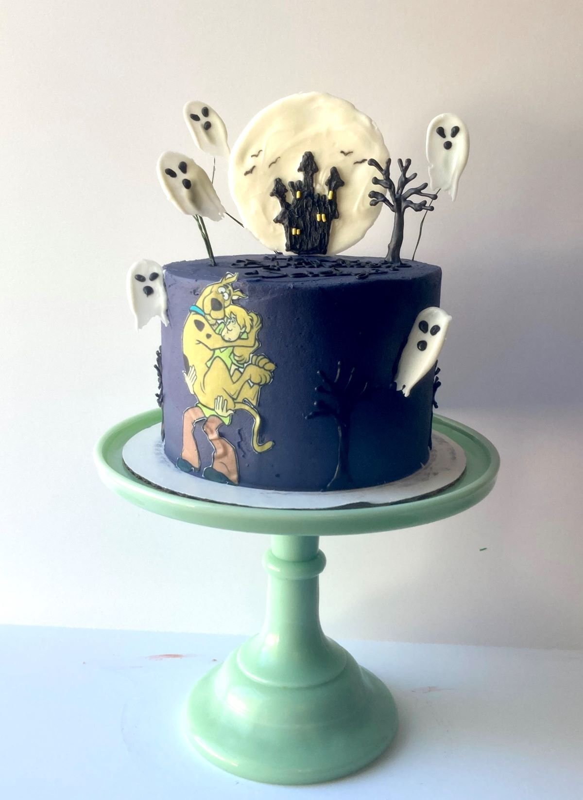 Cake with chocolate ghosts, trees, and moon with castle and edible image of Scooby Doo and Shaggy