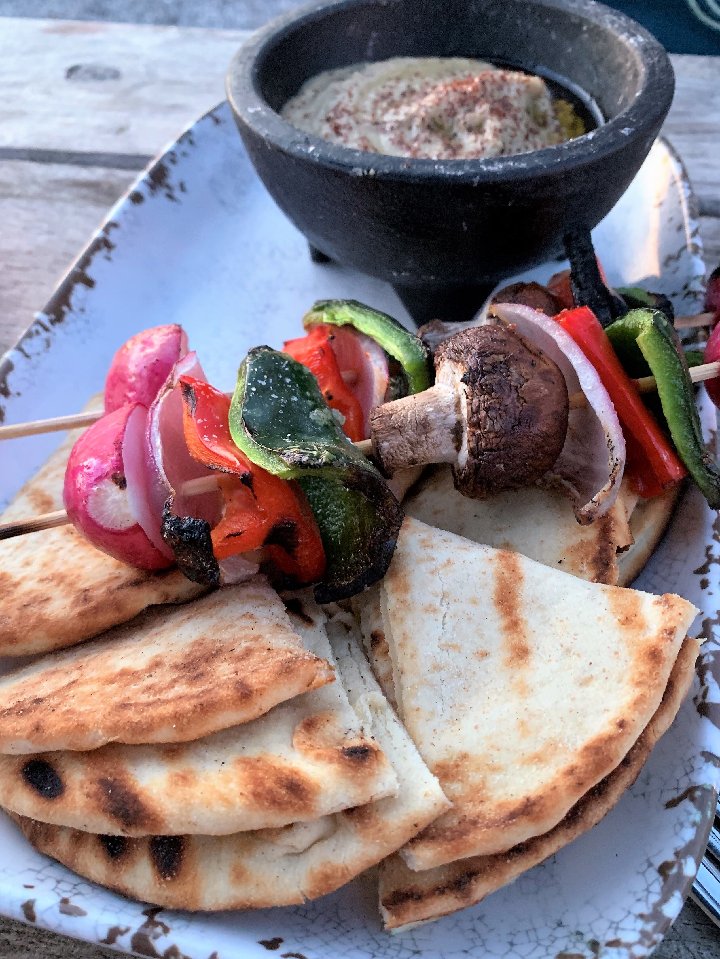 vegetable skewers and flatbread on a plate in front of roasted eggplant dip in a bowl