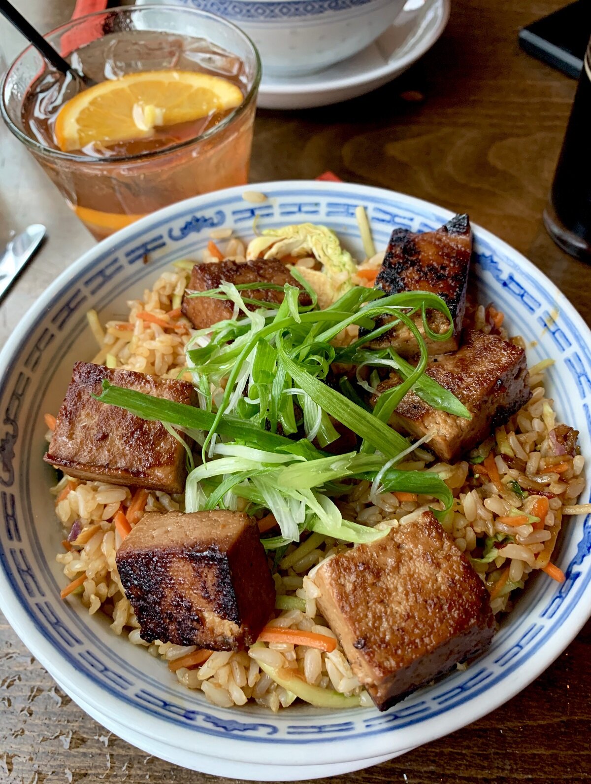 bowl of fried rice topped with tofu cubes with a cocktail