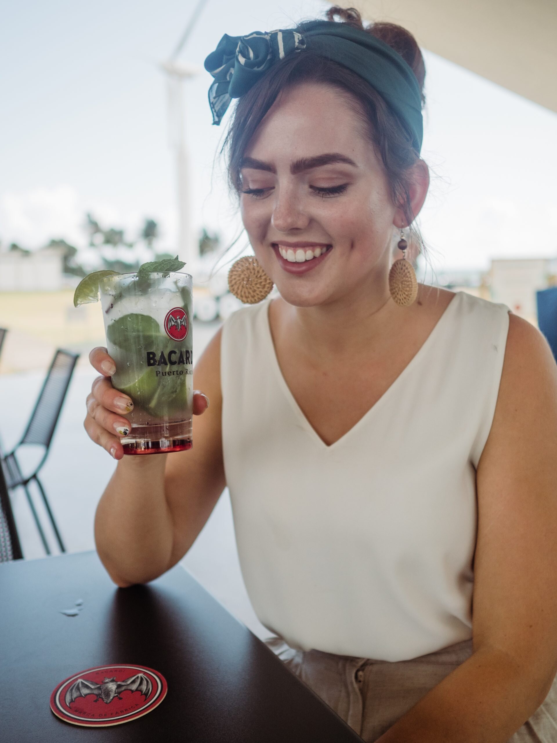 Drinking Bacardi mojitos at the distillery in Puerto Rico wearing a white blouse and headscarf and wooden circular earrings