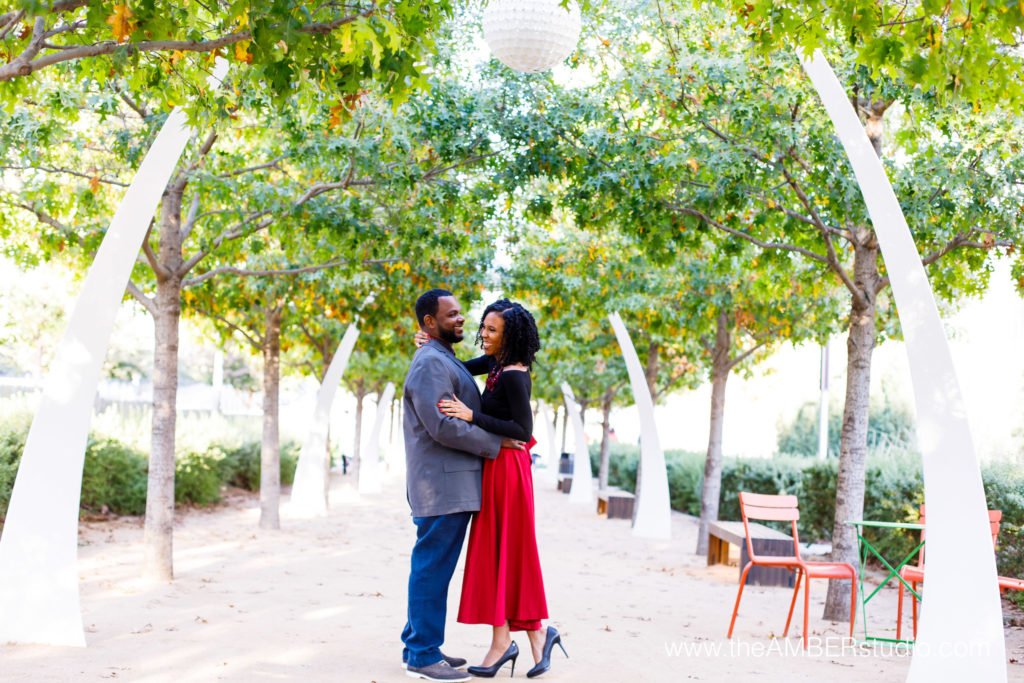 The arches at Klyde Warren Park are a great Dallas engagement session location. Black wedding photographer capture this image of an African American couple embracing each other and laughing under the arches.