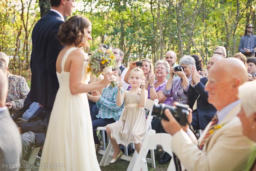 little girl giving thumbs up as bride and groom walk down aisle