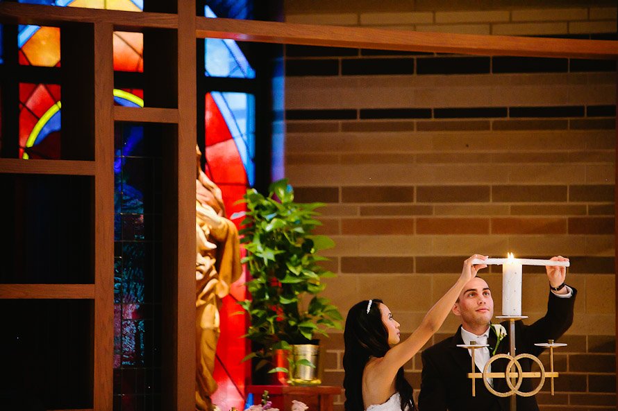bride and groom lighting unity candle in Catholic church