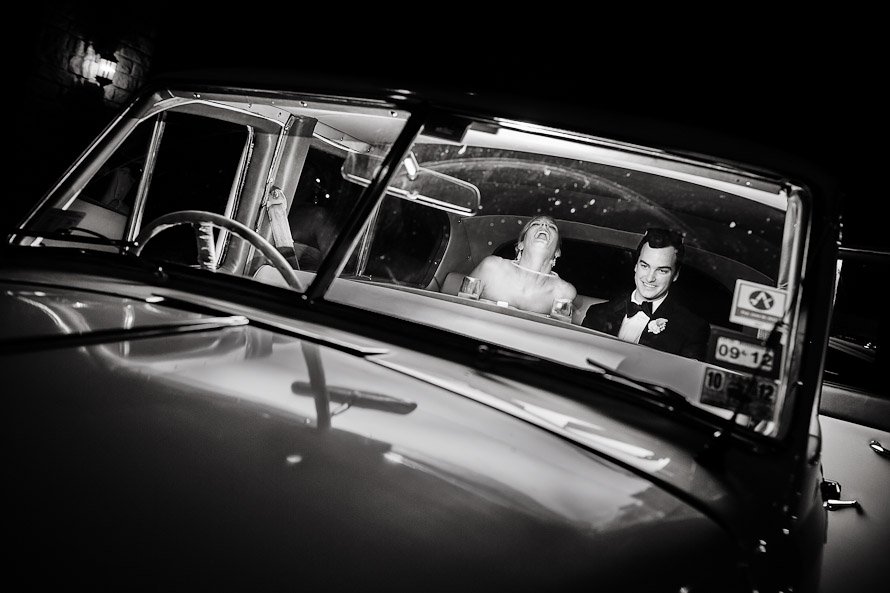 bride and groom exiting reception in vintage car
