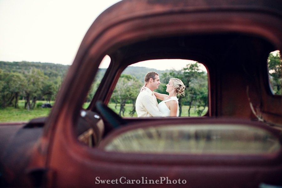 bride and groom kissing through window of old rusty red truck