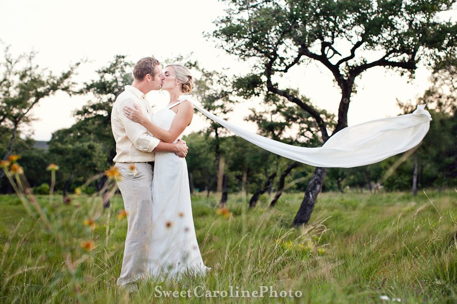 bride and groom kissing with dress flowing in wind