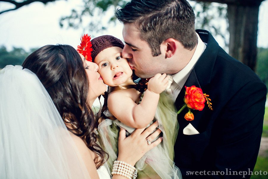 bride and groom kissing daughter on cheek