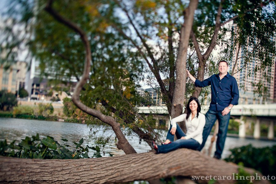 couple standing and sitting on tree during Austin engagement photos