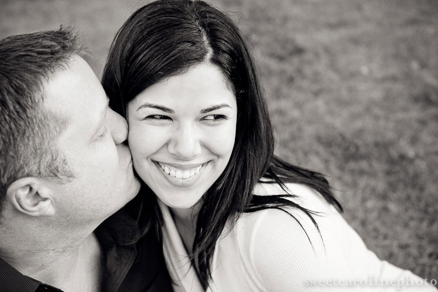 couple kissing in black and white while sitting on grass