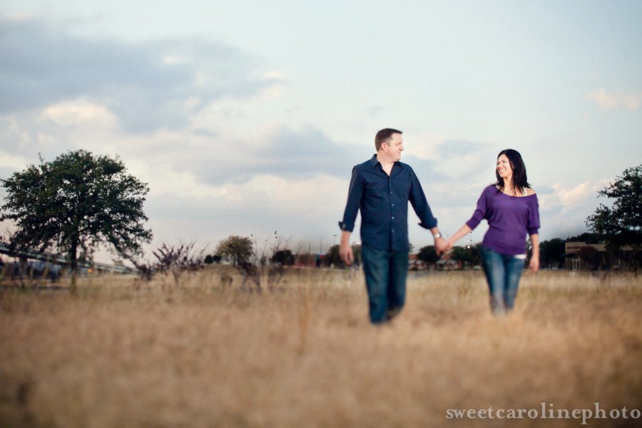 couple walking through field together during Austin engagement photography