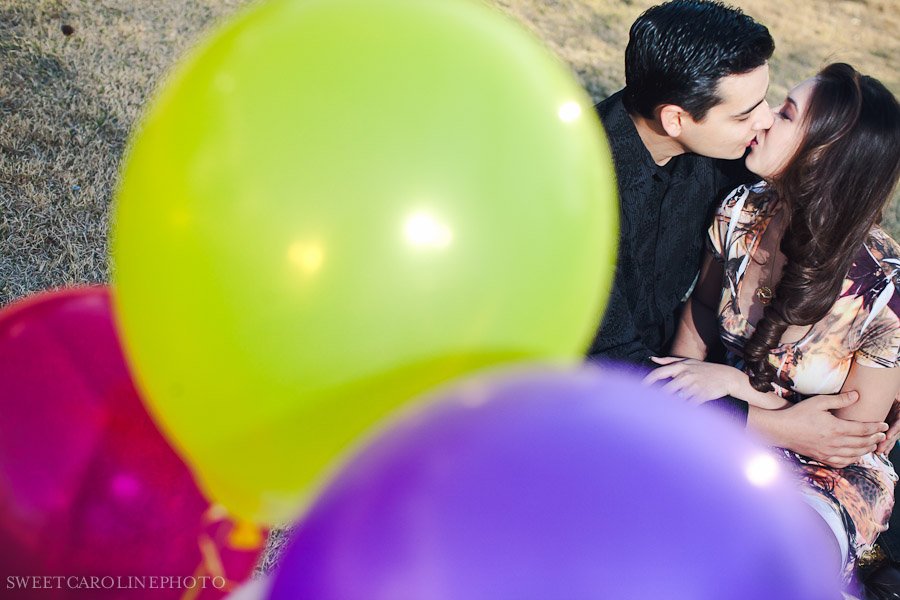 couple kissing in between yellow and purple balloons