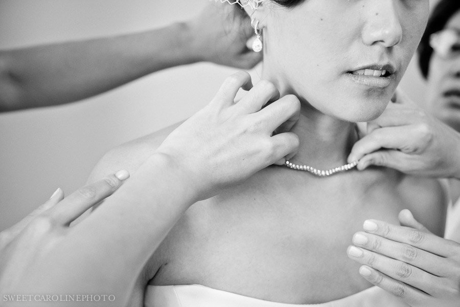 bridesmaids putting necklace on bride
