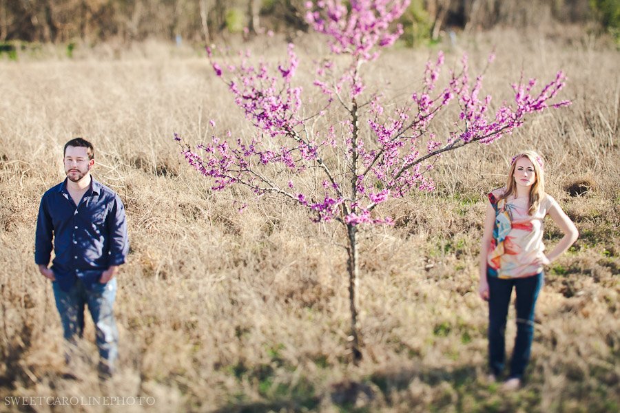 couple standing by tree with pink flowers in Austin field