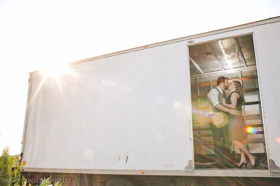 couple kissing in old truck with lens flare