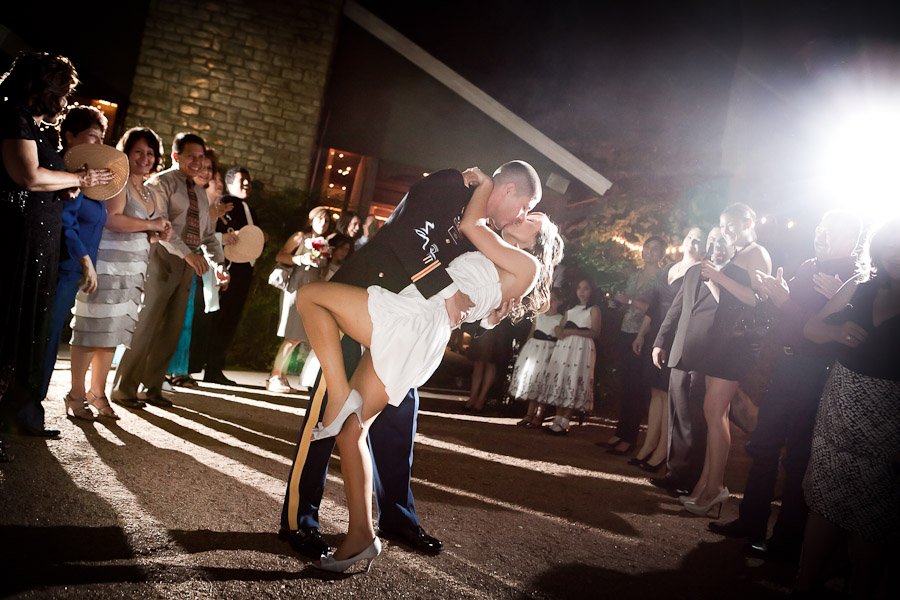 Classic dip and kiss photograph as the bride and groom exit the receptio in front of the guest
