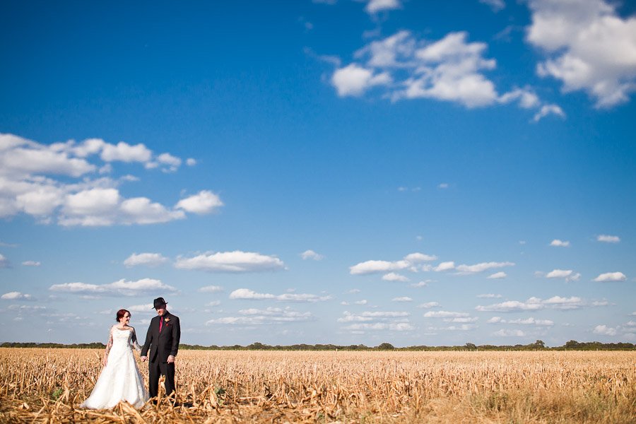 Alternative Bride and Groom portrait holding hands in a dried cornfield