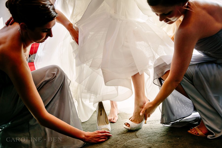 bride putting shoes on about the go to ceremony