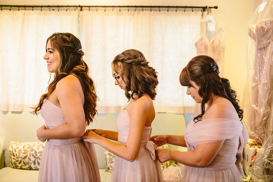 bridesmaids tying dresses in row
