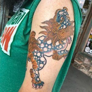 Foo dog tattoo on upper arm, one of the beautiful tattoos done by Tan Vo in Long Beach.