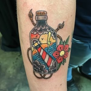 American traditional tattoo of a bottle containing a lighthouse and the ocean by Sof PMA.