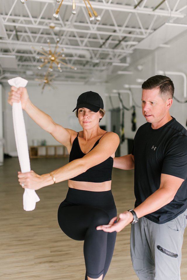 seersucker + mark morgan fitness by popular Indianapolis fitness blog, Seersucker and Saddles: image of a woman doing an exercise move next to male workout instructor Mark Morgan inside workout studio Fit, Flex, Fly.