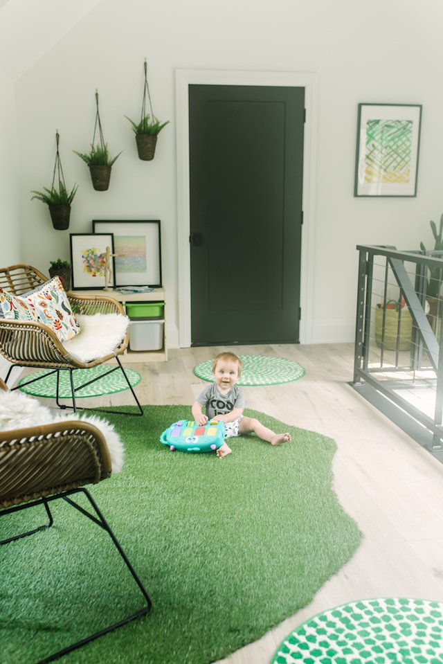 Walmart Kids by popular Indianapolis life and style blog, Seersucker and Saddles: image of a loft space decorated with a green turf rug, green and white polka dot rug, faux plants in hanging baskets, and rattan chairs with sheep skin throws and colorful throw pillows. 