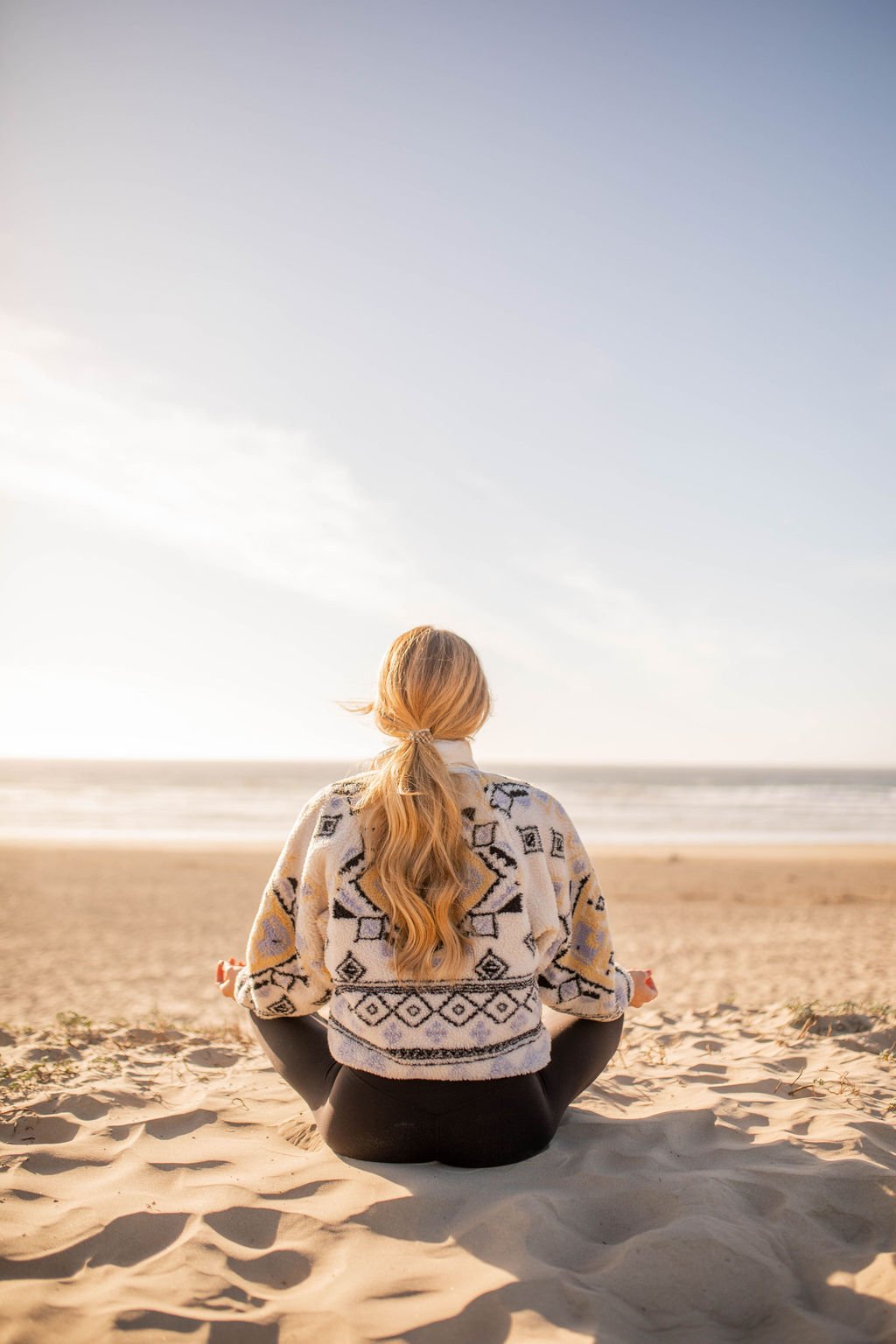 Woman sitting on the beach practicing self-care meditation