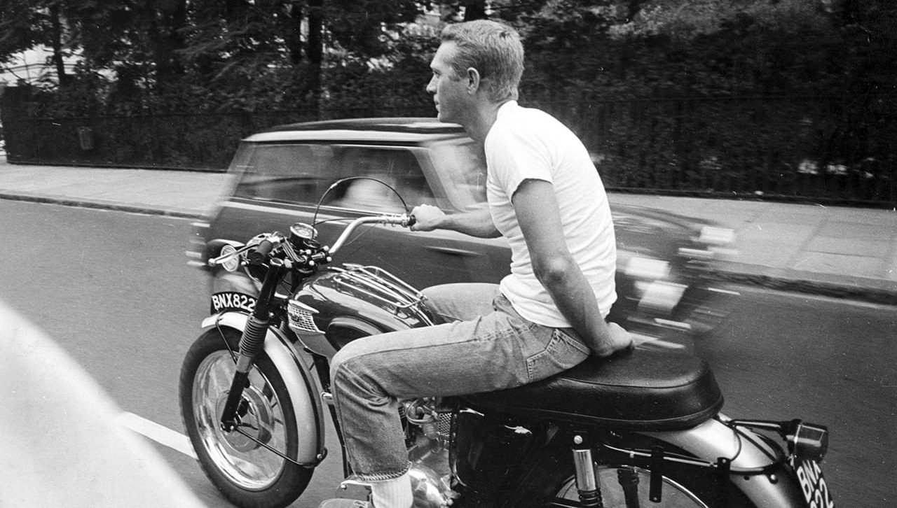 Steve McQueen riding a motorcycle with white socks
