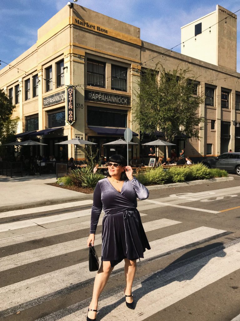 nicolette wears a grey blue wrap dress and is standing in a crosswalk
