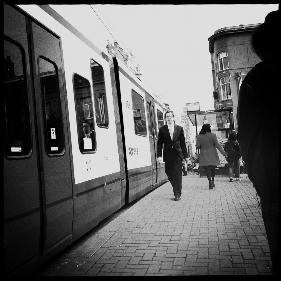 Black and white photograph of a man walking next to a Tram in Amsterdam taken with the iPhone and Hipstamatic