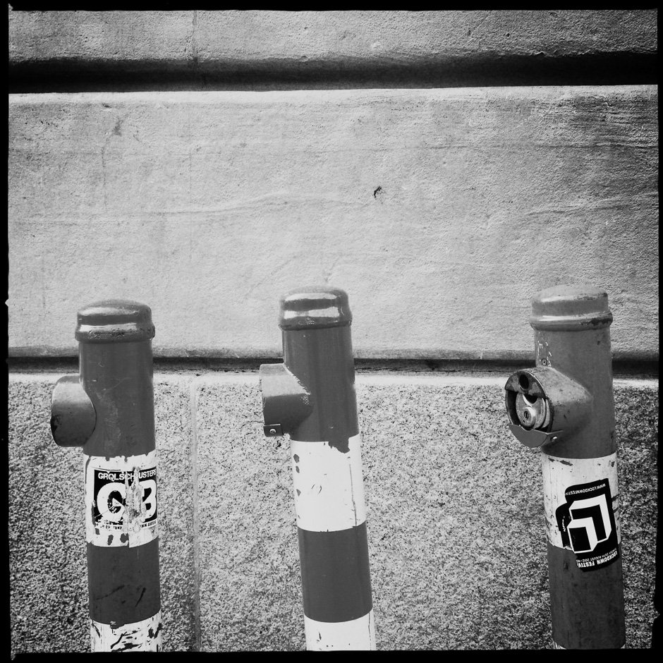 Black and White photograph of 3 metal poles against a wall taken with the iPhone and Hipstamatic