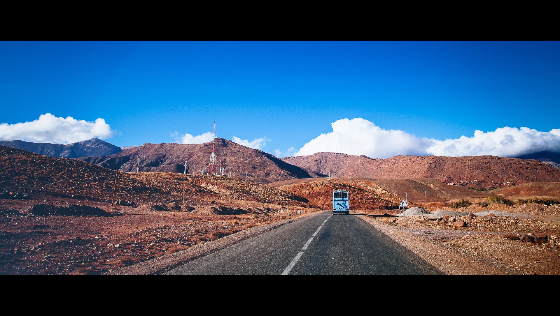 A highway in the Moroccan high atlas, with a bus in the background
