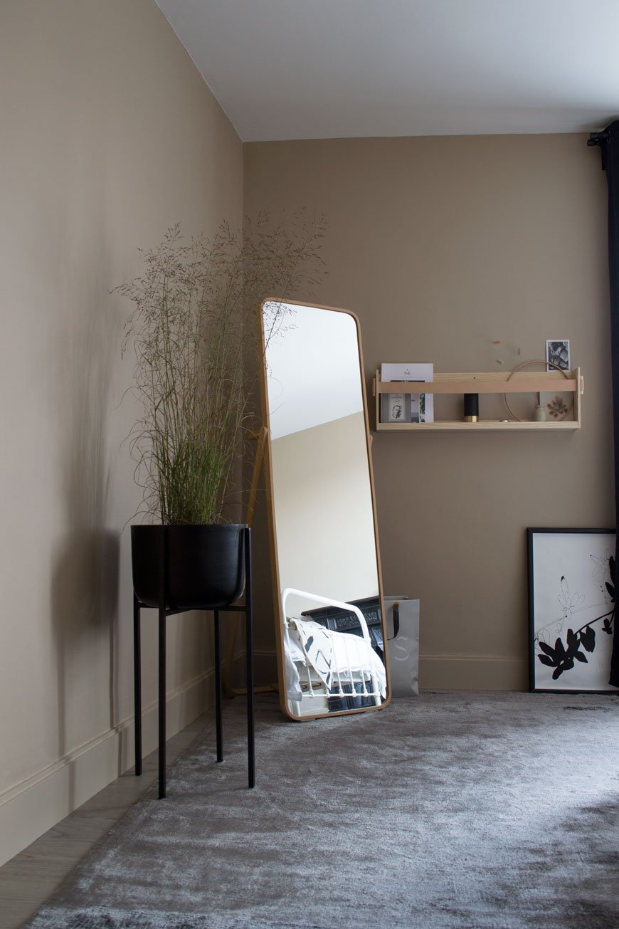 Looking into the bedroom with a light grey rug, floor length mirror and Nordic luxe look.