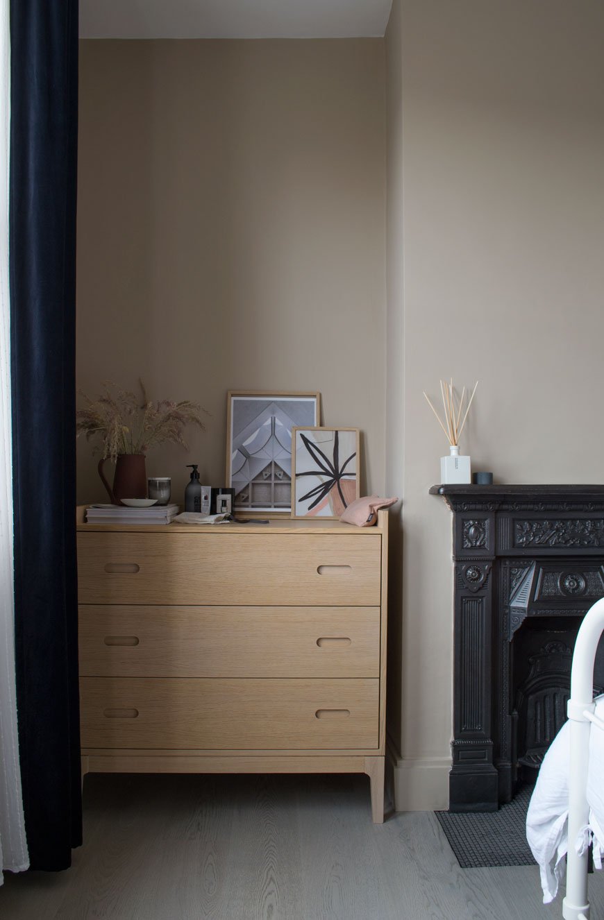 An oak chest of drawers in a beige bedroom with a Nordic luxe style. 