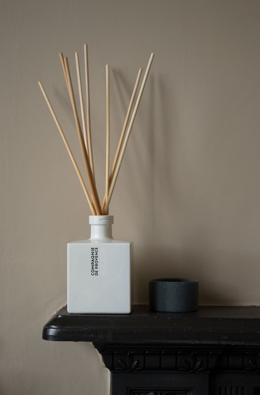 A white room diffuser and sweet little ceramic pot in a beige bedroom with Nordic luxe style.