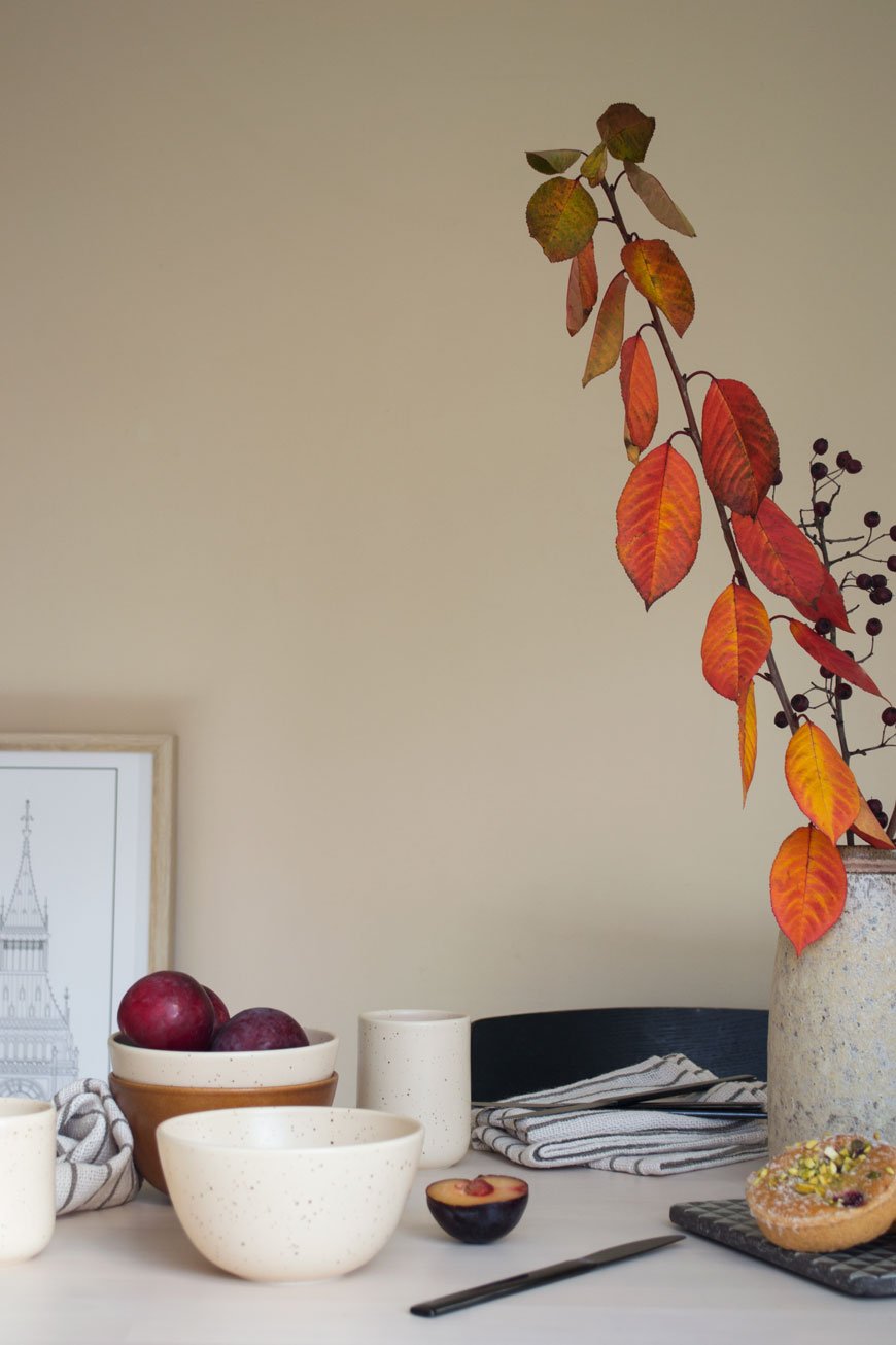 how to style your home for winter using rusty orange autumn leaves styled in a vase on the dining table with tableware from NABO
