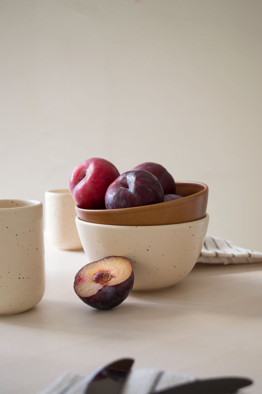 A bowl of plums styled in a stack of bowls, made in Denmark for NABO shop.