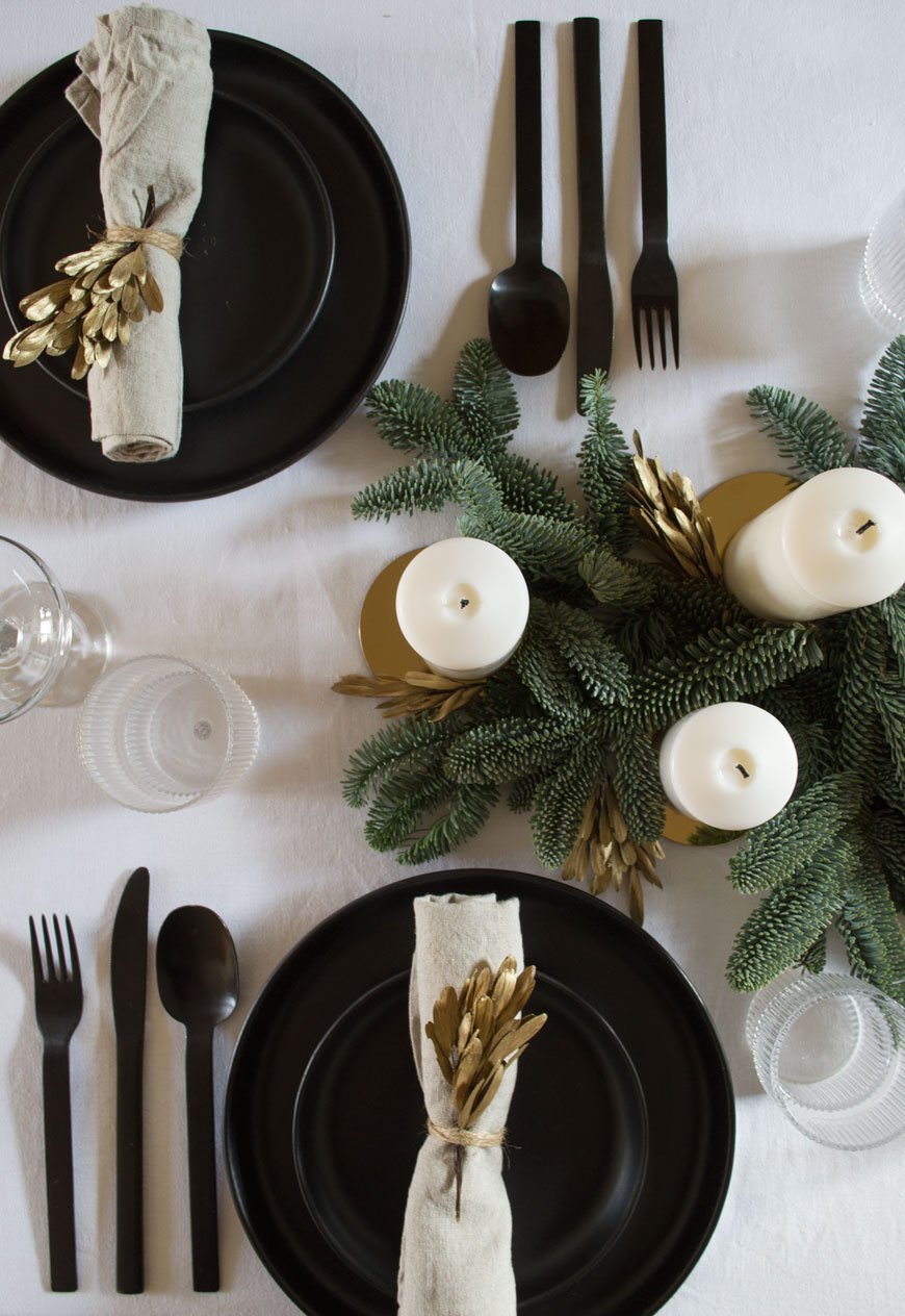 Black, white and gold Nordic Christmas table styling with black plates and cutlery.