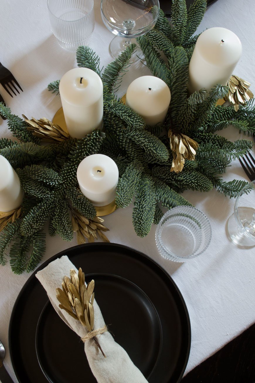 A minimally styled blue spruce and white candle table centrepiece for a very Nordic Christmas.